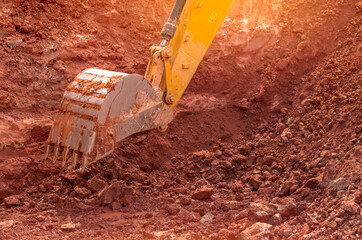 Backhoe working by digging soil at construction site. Bucket of backhoe digging soil. Crawler...