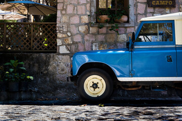 Carro viejo azul clasico en carretera de piedra entre la naturaleza con rines originales y luz...
