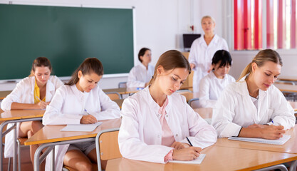 Group of focused female medical students writing notes in auditorium