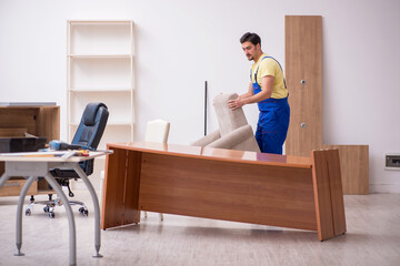 Fototapeta na wymiar Young male carpenter repairing arm-chair in the office