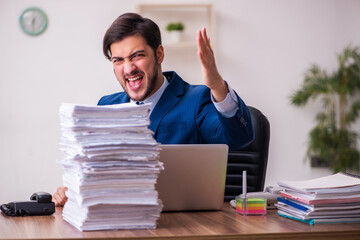 Young businessman employee unhappy with excessive work in the office