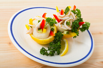 Delicious salad of calamari, cucumber, red pepper and greens in lemon filled with olive oil and Greek yogurt sauce