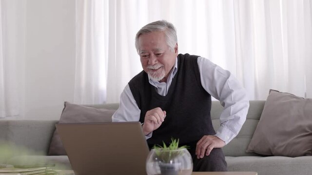 Elderly Asian man video conferent online with teblet at home.
