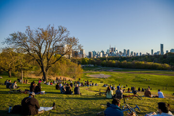 Downtown Toronto Canada panoramic cityscape skyline view over Riverdale Park in Ontario. people resting on grass. Picnic outside. sunset time