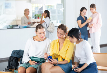 Fototapeta premium Group of smiling young woman students chatting in break between lessons in hallway