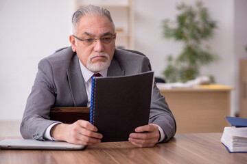 Old male employee working in the office