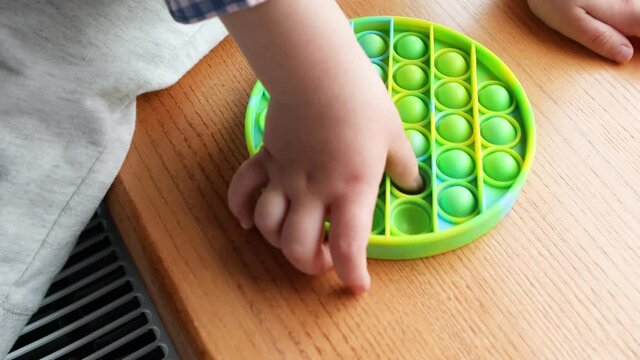 child playing with the Pop It fidget. Rainbow Pop it fidget toy
