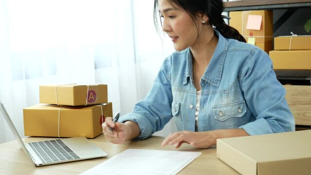 Online seller Close up hands Young asian woman typing laptop keyboard checking online order, check goods stock delivery package shipping postal. Asian woman startup small business at home office