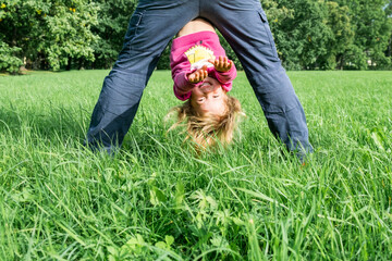 Father and daughter spending time on the field. Father holding daughter upside down. She is smiling. Concept of friendly family. Great family vacation.