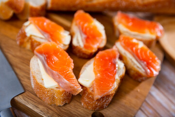 Delicious sandwiches with smoked salmon and butter on wooden serving board..