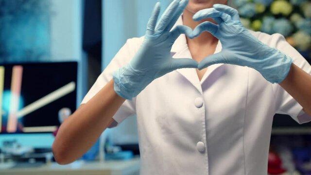 A nurse makes a heart shaped hand sign to a patient as a kind gesture