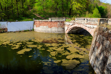 Old arched brick bridge across a pond in Sharovka Palace park in in Kharkov region, Ukraine