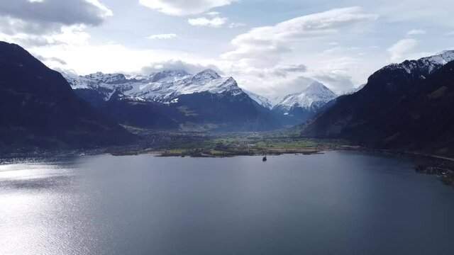 Snow-capped mountains with the famous Bristen summit, thrones over the deep blue Uri Lake, drone shot in Switzerland