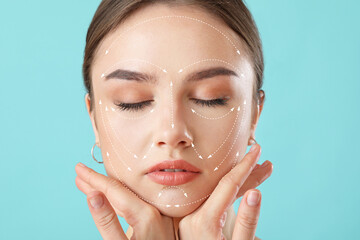 Young woman with arrows for massaging on her face against color background