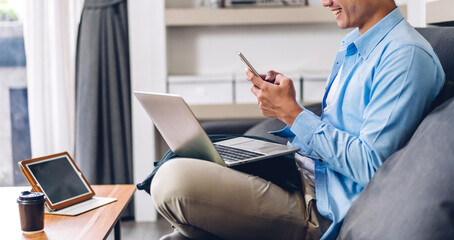 Young smiling asian man relaxing using laptop computer working and video conference meeting at...