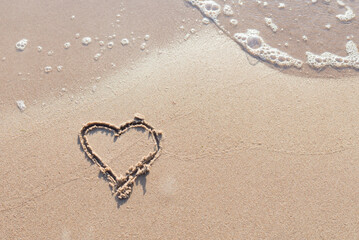 One Heart Drawn in the Sand on a Beach.soft wave of the sea.Romantic love. true love.Beige beach