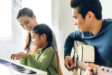 Portrait of enjoy happy love asian family mother and little asian girl child smiling and having fun teaching and play piano music lesson at home