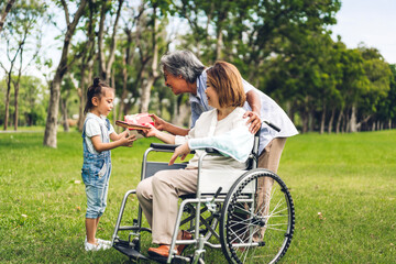 Portrait of happy asian grandfather with grandmother and asian little cute girl enjoy relax in summer park.Young girl with their laughing grandparents smiling together.Family and togetherness