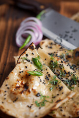 Close-up of fresh, hot tandoori roti or butter naan garnished with black till and green fresh...
