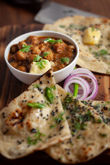 Close-up of fresh, hot tandoori roti or butter naan garnished with black till and green fresh coriander leaves. A typical, traditional north indian panjabi food.