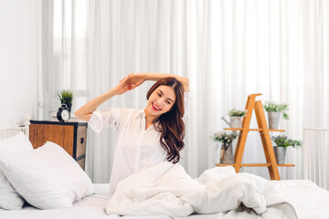 Portrait of smiling cheerful beautiful pretty asian woman clean fresh healthy white skin posing in pajamas white clothes.Girl felling relaxing and enjoy time on the bed at home.asia beauty