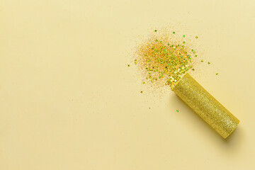 Party popper and confetti on color background