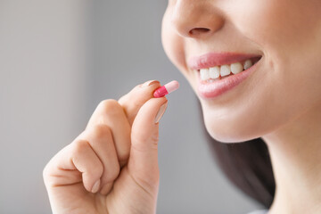 Beautiful young woman taking pills at home, closeup