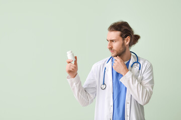 Thinking doctor with pills on color background