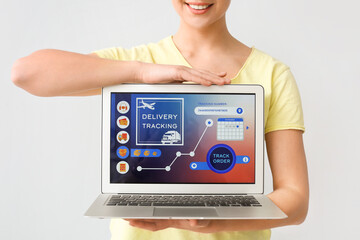 Woman and laptop with open page of delivery service application on light background