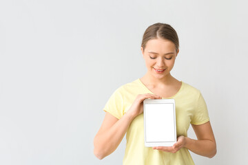 Fototapeta premium Young woman with tablet computer on light background