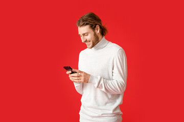 Young man using mobile phone on color background