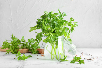 Jar with fresh parsley on light background