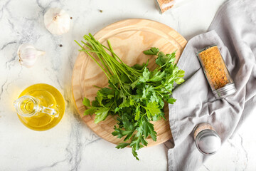 Board with fresh parsley, oil and spices on light background