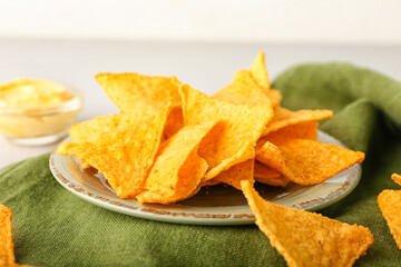 Plate with tasty nachos and sauce on light background, closeup