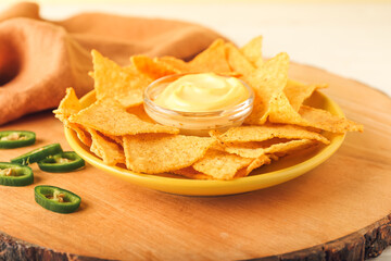 Plate with tasty nachos and sauce on board, closeup