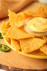 Plate with tasty nachos and sauce on board, closeup