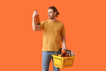 Young man with shopping basket on color background
