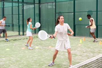Young sporty woman performing basic strokes during paddle tennis group training