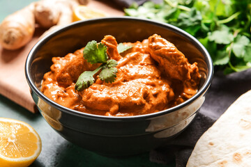 Bowl of tasty chicken tikka masala on table