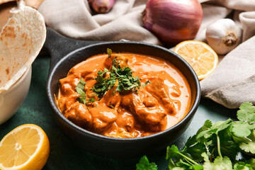 Frying pan of tasty chicken tikka masala on table