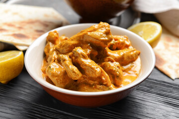 Bowl of tasty chicken tikka masala on table