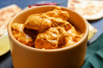 Bowl of tasty chicken tikka masala on table, closeup
