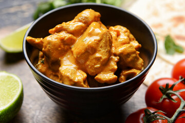 Bowl of tasty chicken tikka masala on table