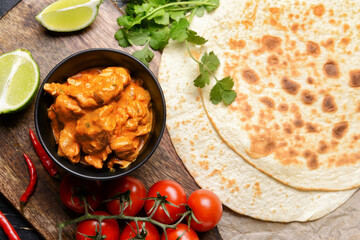 Bowl of tasty chicken tikka masala on table