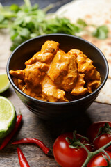 Bowl of tasty chicken tikka masala on table
