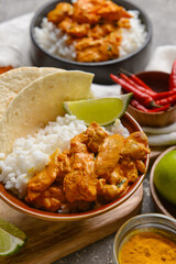 Bowl of tasty chicken tikka masala and rice on table