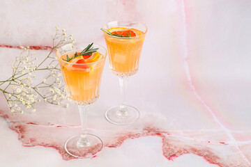 Glasses of tasty grapefruit cocktail and flowers on light background