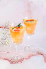 Glasses of tasty grapefruit cocktail and flowers on light background