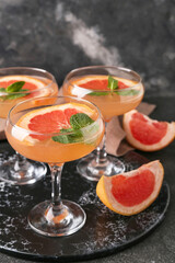 Glasses of tasty grapefruit cocktail on dark background