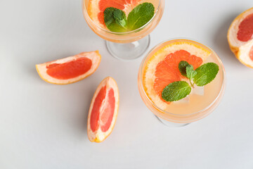 Glasses of tasty grapefruit cocktail on grey background